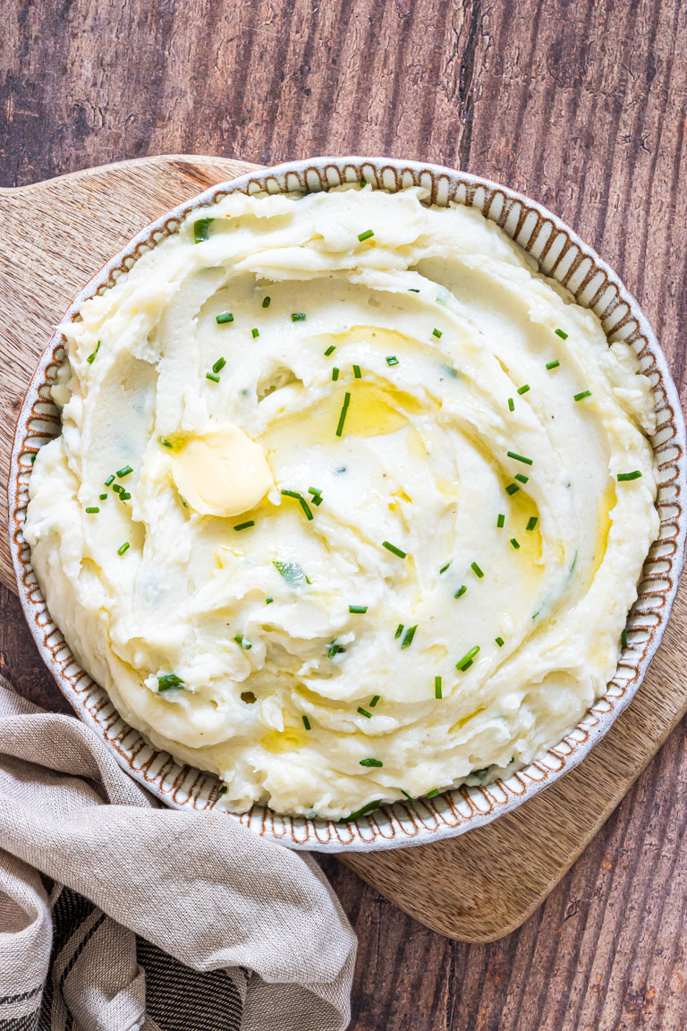 crockpot mashed potatoes served in a ceramic bowl with a cloth napkin