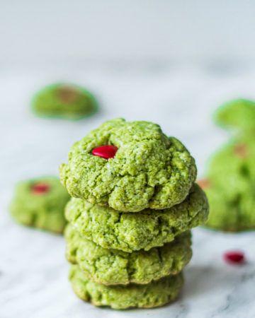 four grinch cookies stacked on top of one another