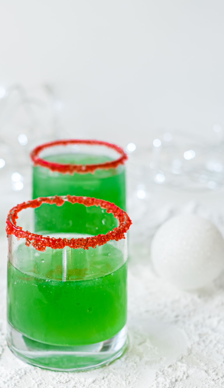 two glasses rimmed with red sugar and filled with Grinch punch