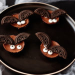 four of the completed bat halloween cookies served on a plate