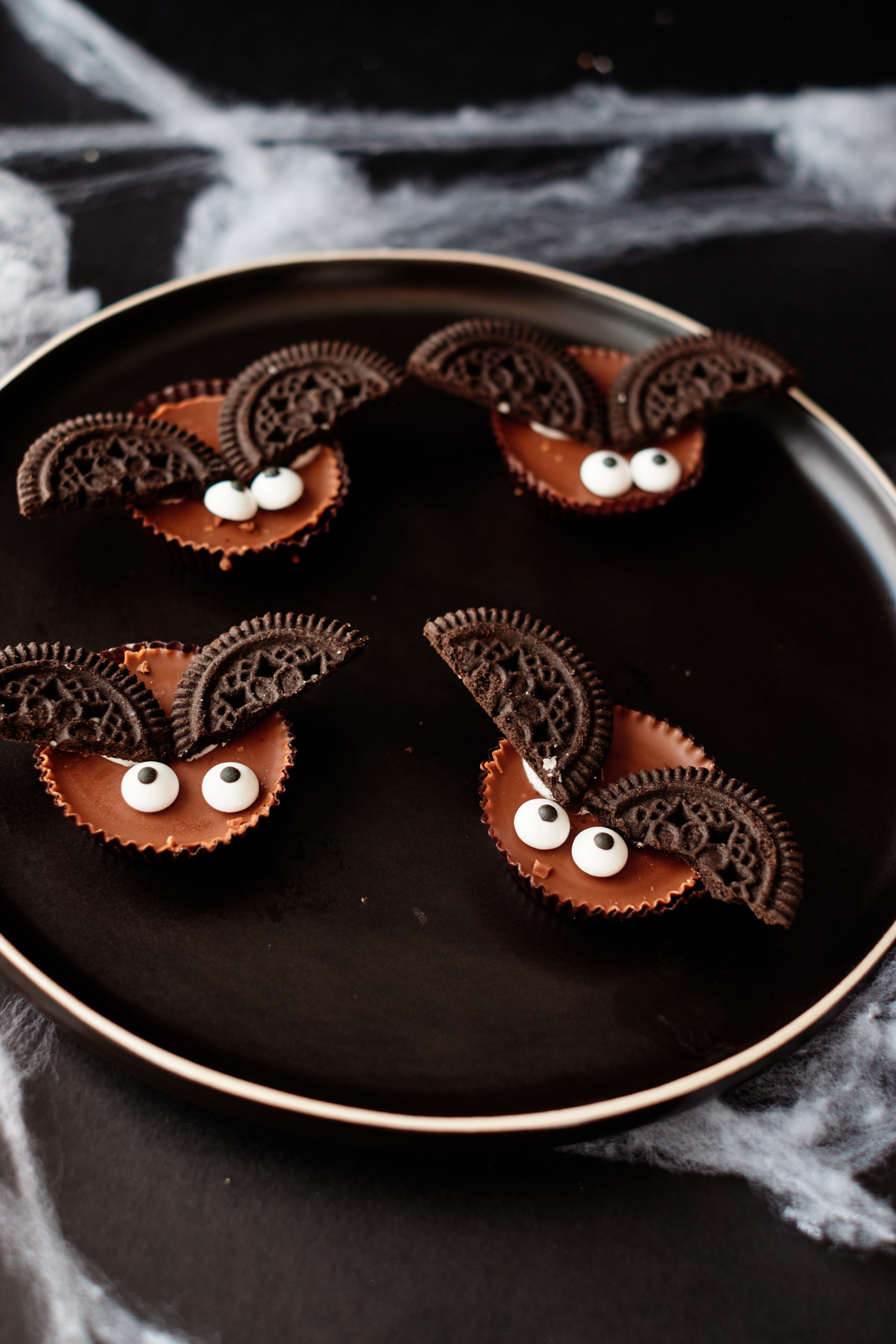four of the completed bat halloween cookies served on a plate