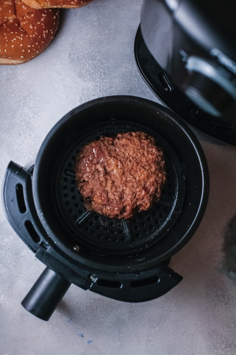 top down view of a cooked turkey burger inside the air fryer basket