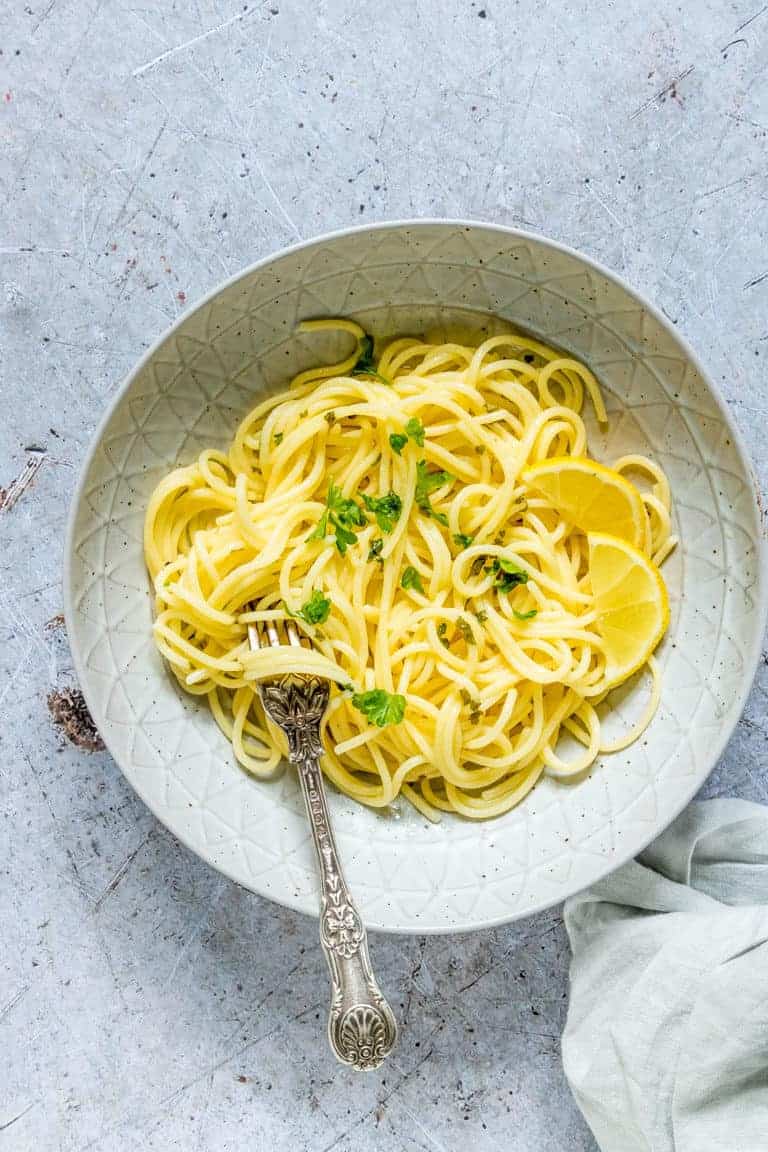 One portion of pasta with Lemon Garlic Butter Sauce served in a white bowl with a silver fork