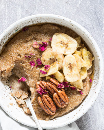 the finished teff porridge topped with banana and nuts and served with a spoon and cloth napkin