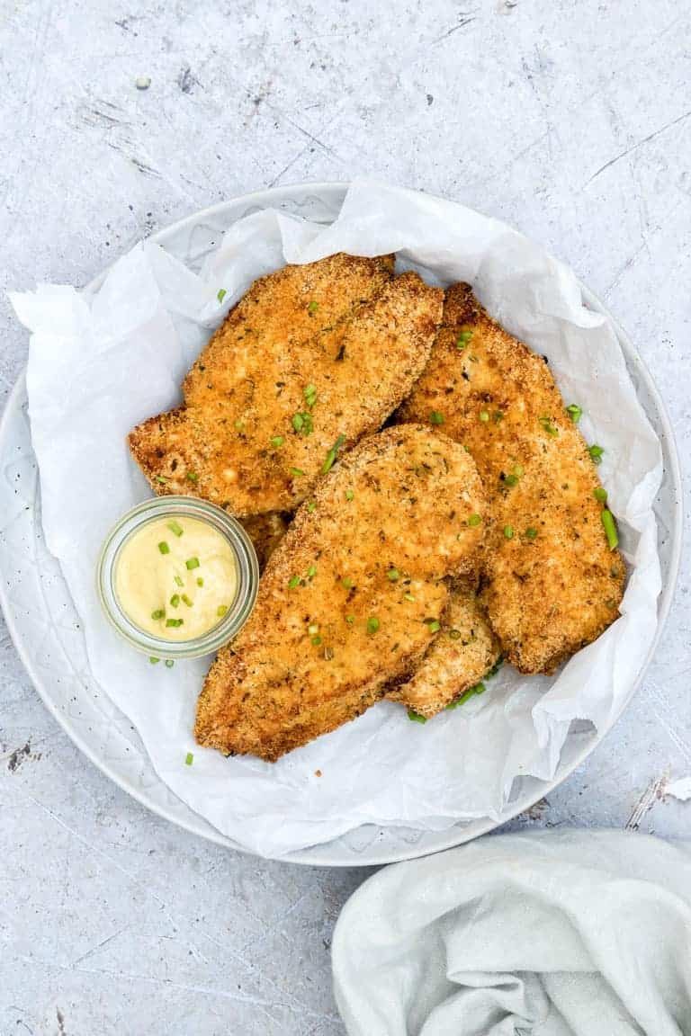 The finished Air Fryer Bonesless Chicken Breast Recipe on a white platter and ready to serve with a side of dipping sauce