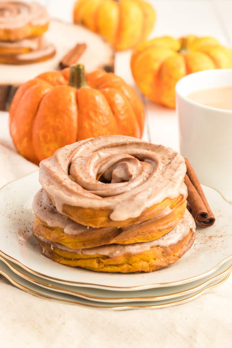 air fryer crullers served on a plate with mini pumpkins and a cinnamon stick