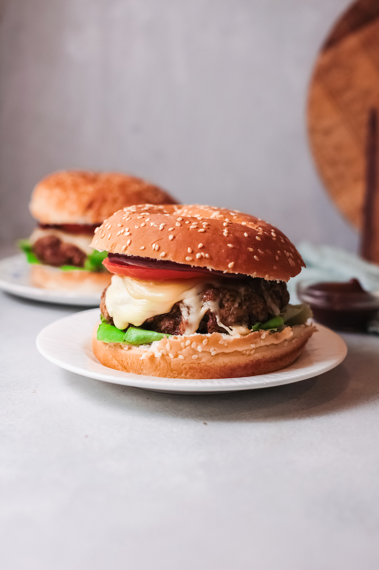 two turkey burgers that have been cooked in the air fyer served on buns and topped with tomato, lettuce and cheese