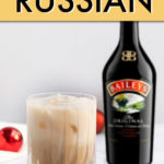 A glass of white russian cocktail on a coaster with a bottle of Baileys irish cream in the background