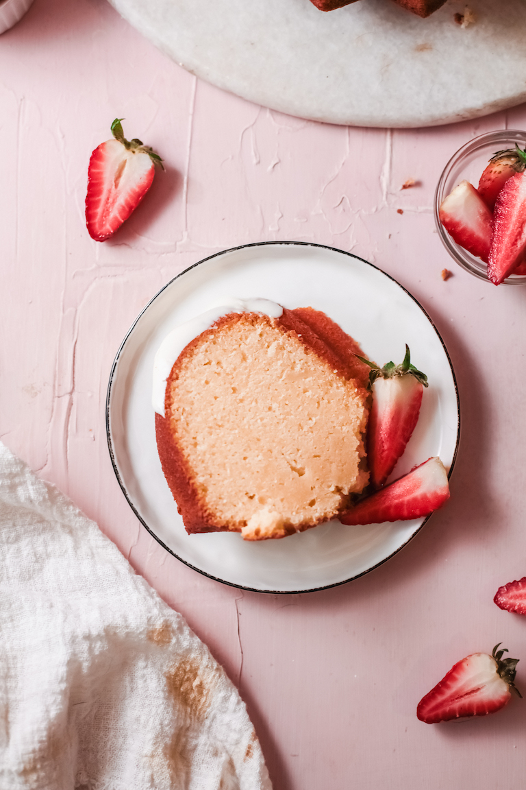 top down view of a slice of pound cake served with strawberries on a white dessert plate