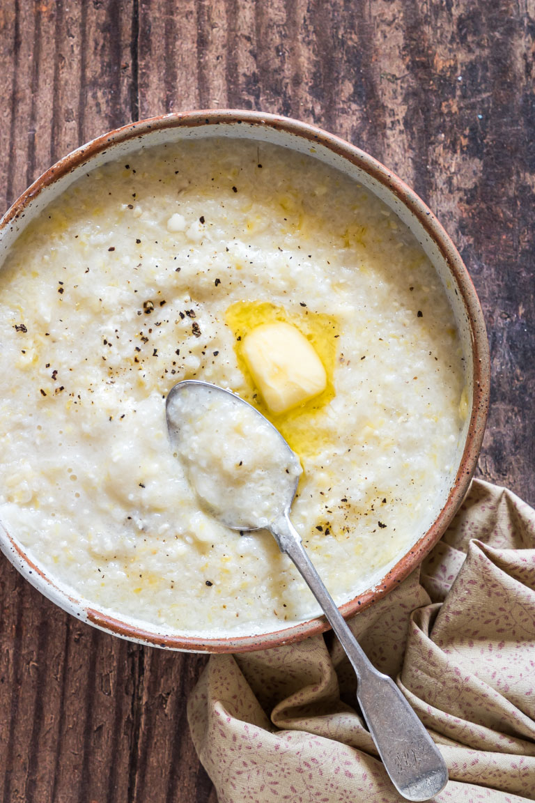 creamy southern style crockpot grits served in a ceramic bowl with a spoon