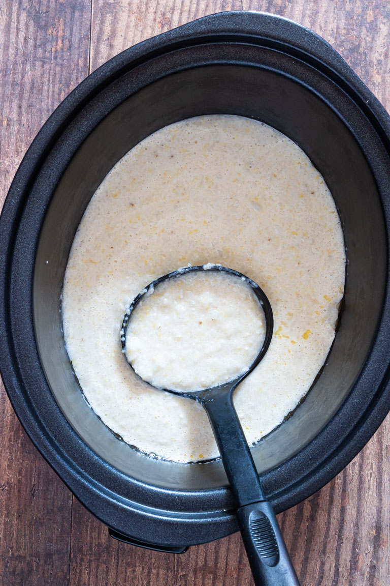 cooked grits inside the crockpot with a ladle ready to serve
