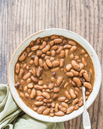 a bowl of the crockpot pinto beans served with a cloth napkin and silver spoon