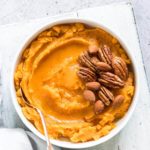 slow cooker mashed sweet potatoes topped with nuts in a serving bowl