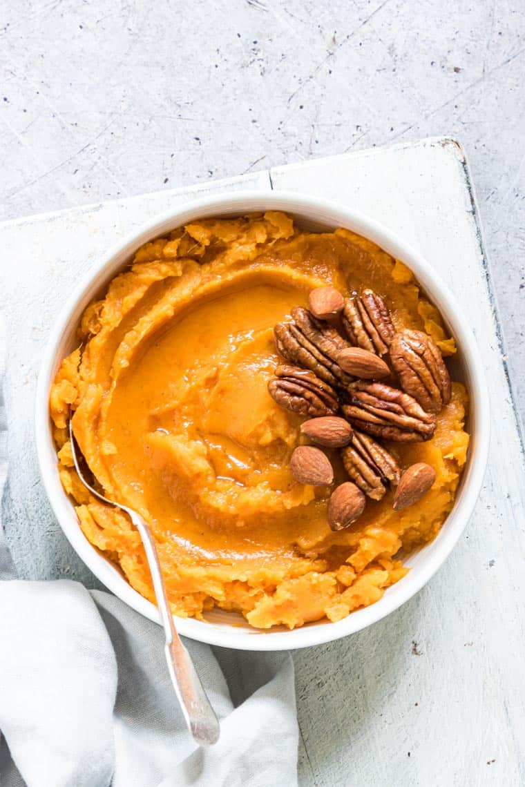 slow cooker mashed sweet potatoes topped with nuts in a serving bowl