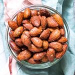 top down view of a bowl filled with air fryer candied almonds set on top of pink and blue linen napkins