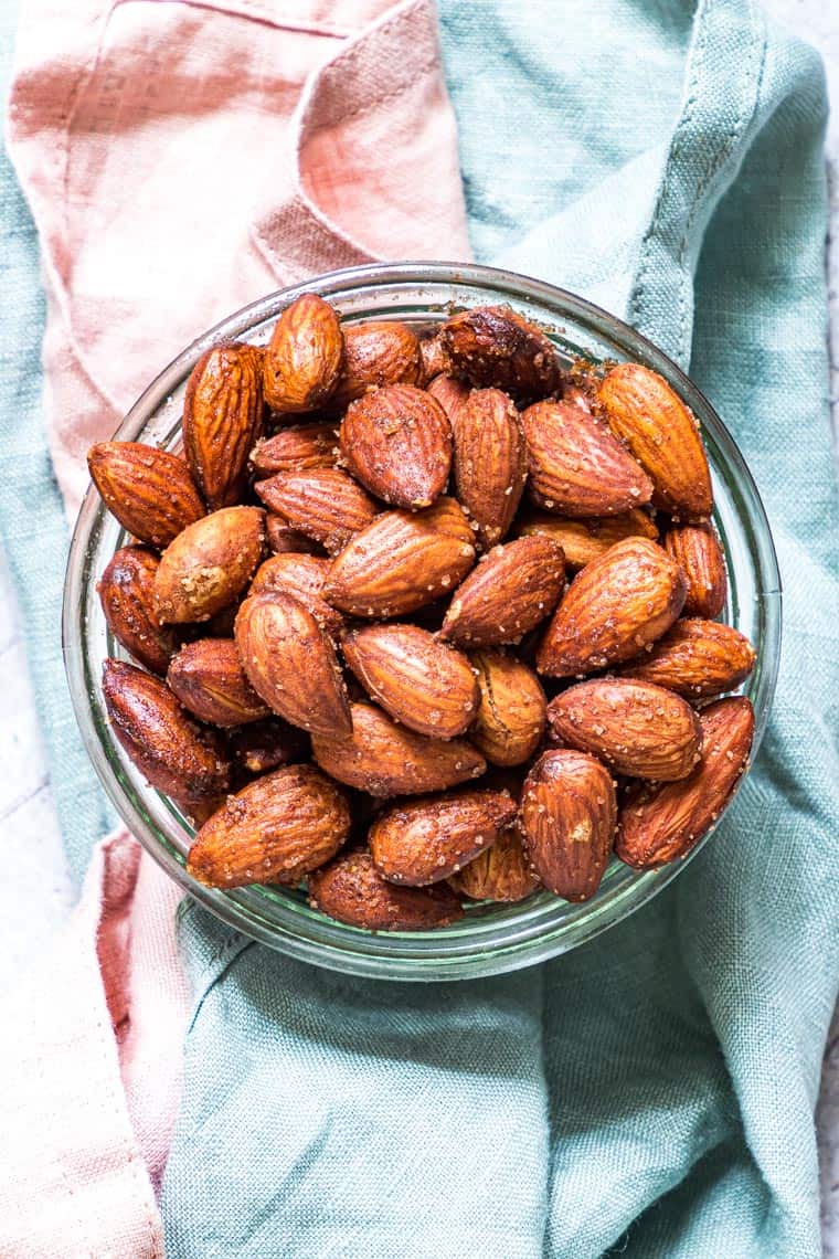 top down view of a bowl filled with air fryer candied almonds set on top of pink and blue linen napkins