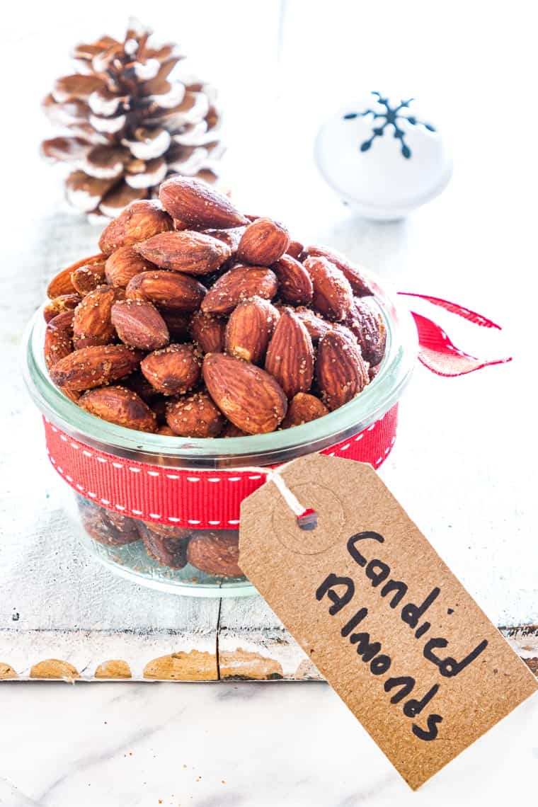 جرة مليئة باللوز السكر ملفوفة في علامة هدية عطلة وقوس أحمر