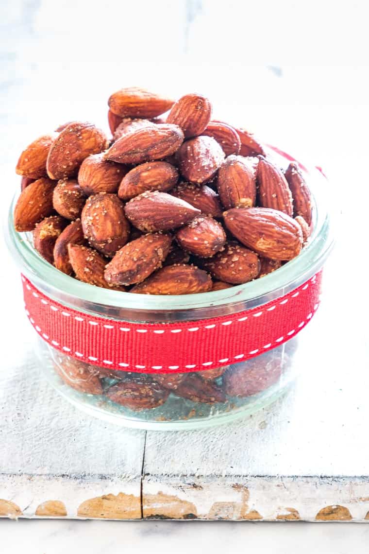 منظر عن قرب لقنينة زجاجية مملوءة باللوز السكر على مقلاة الهواء ملفوفة في قوس هدية حمراء