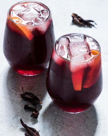 two glasses of Jamaican Sorrel Drink next to dried hibiscus.
