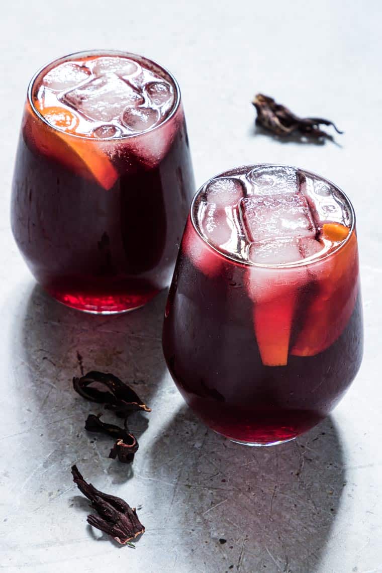 two glasses of Jamaican Sorrel Drink next to dried hibiscus.