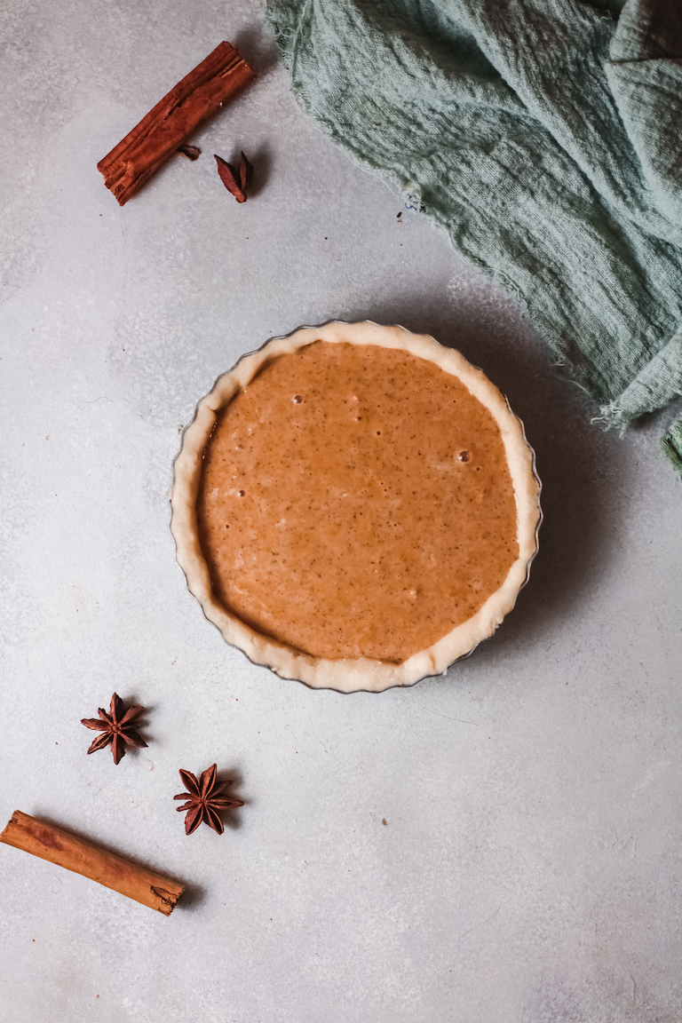 one sweet potato pie on a counter next to a blue cloth kitchen towel