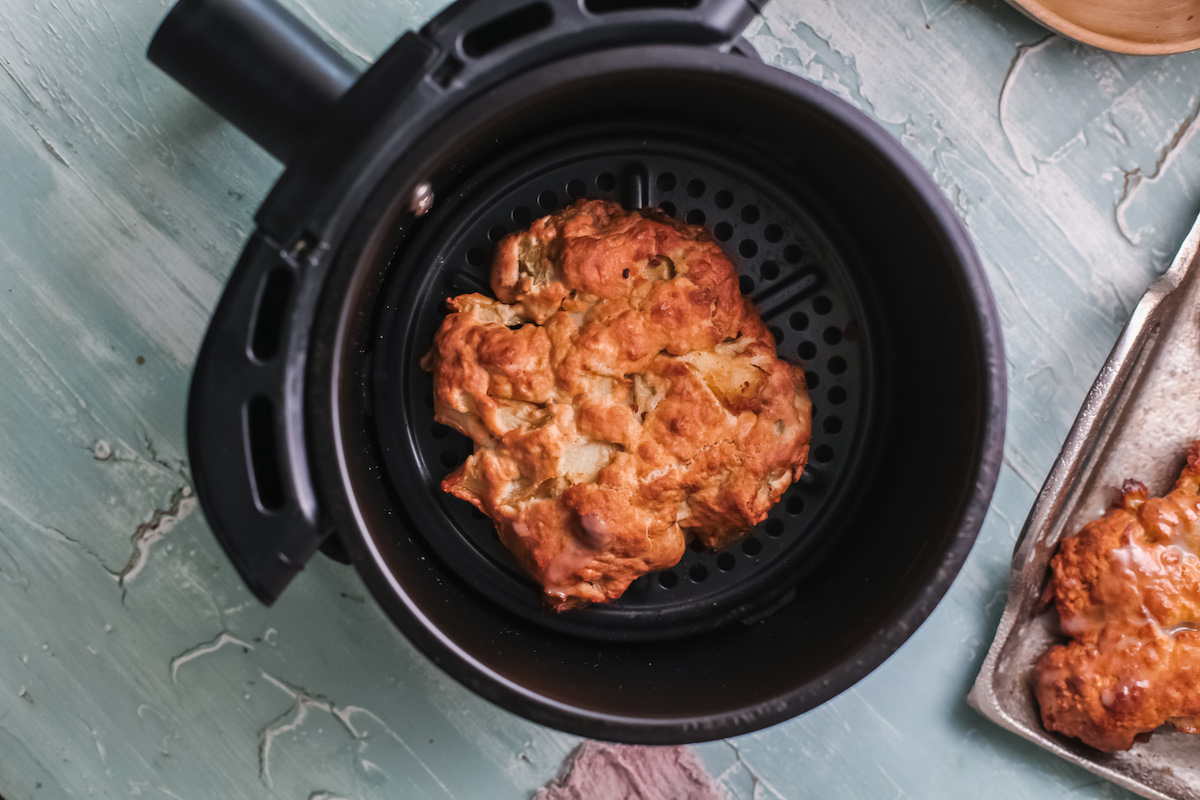 close up view of a cooked apple fritter inside the air fryer basket