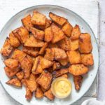 a plate filled with air fryer butternut squash fried and a cup of dipping sauce