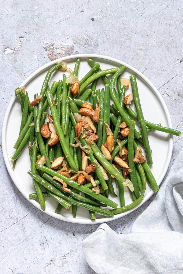 Green Beans Almondine served on a white plate with a cloth napkin
