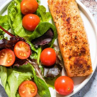 The finished Air Fryer Salmon served on a white plate with a green salad