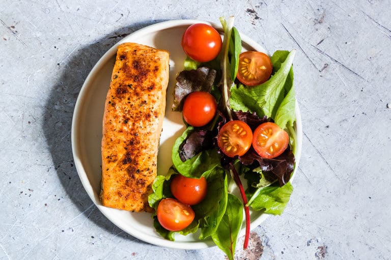 Air Fryer Salmon served with a green salad on a white plate