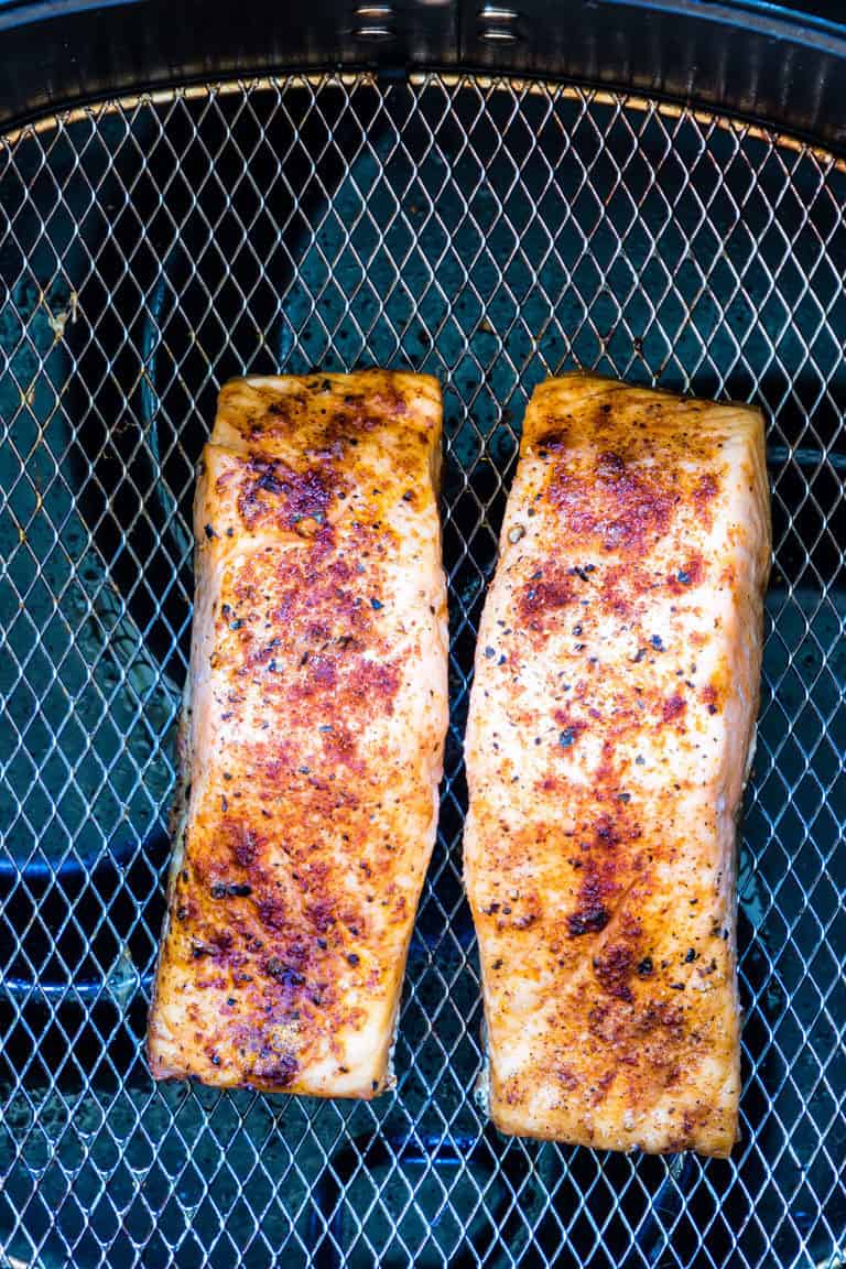 Two cooked Air Fryer Salmon fillets inside the air fryer basket