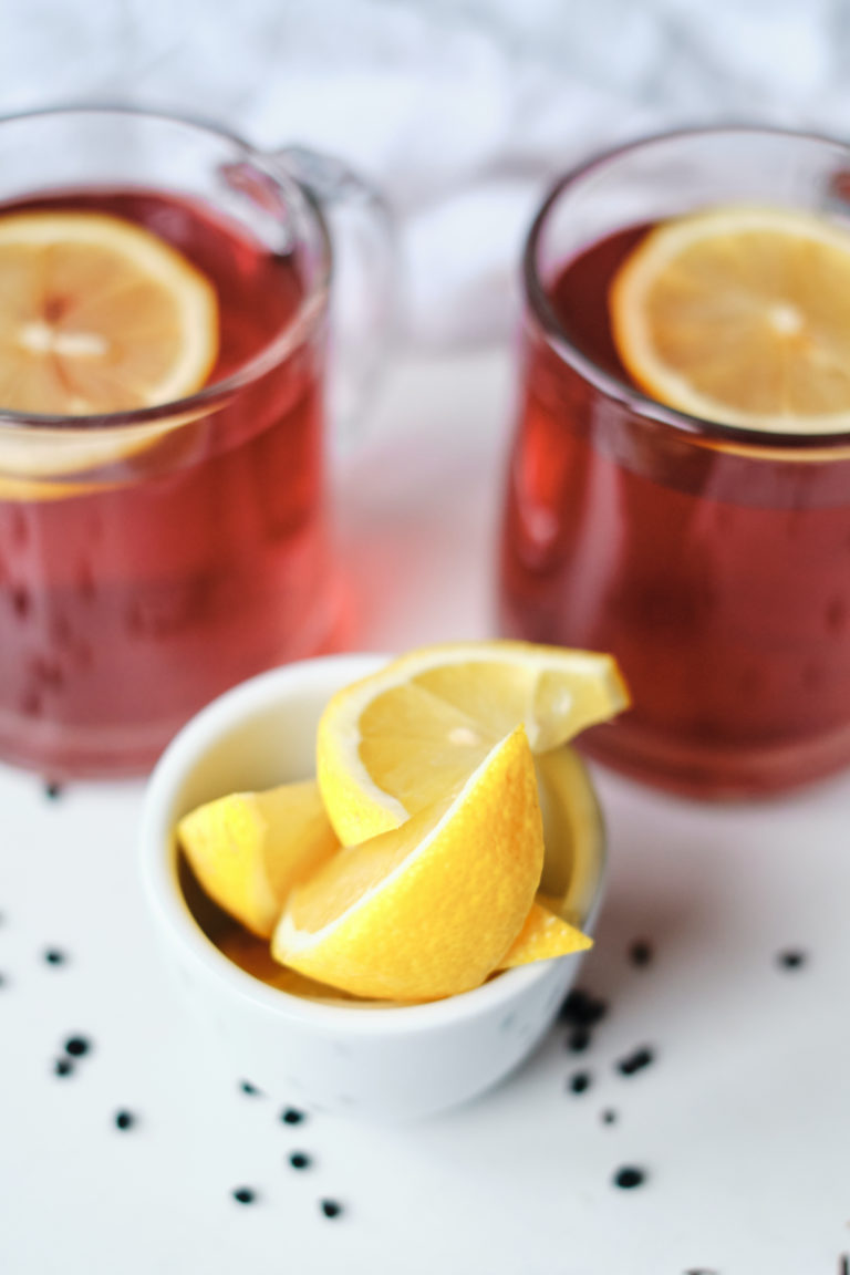 two glass mugs filled with elderberry tea and served with lemon wedges