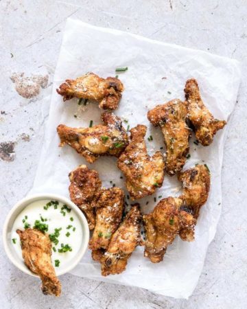 Air Fryer Chicken Wings served with dipping sauce and garnished with fresh herbs
