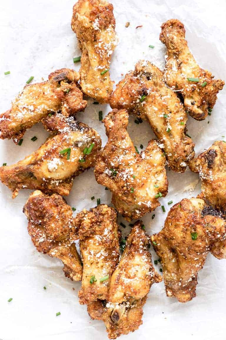 After cooking chicken wings in air fryer they are set on a white parchment and served with dipping sauce