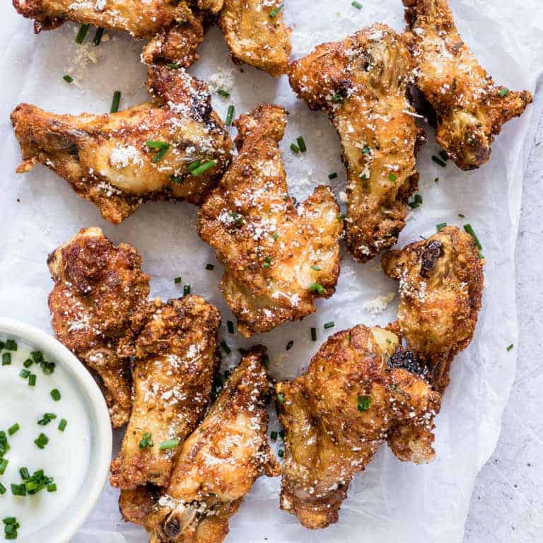 close up of finished Air Fryer Chicken Wings served with ranch dipping sauce and fresh herbs