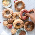 A variety of Air Fryer Donuts next to small bowls filled with sprinkles and dried edible flowers