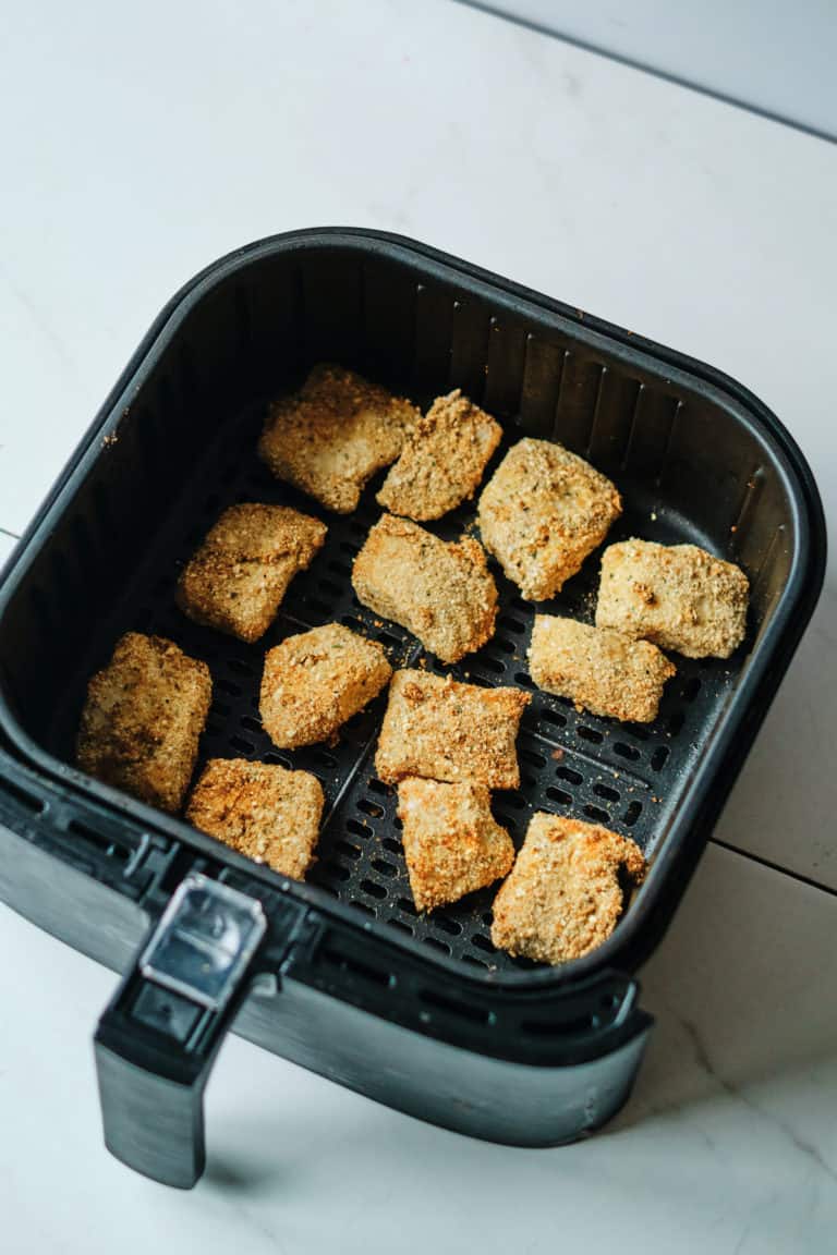 a batch of cooked fish sticks inside the air fryer basket