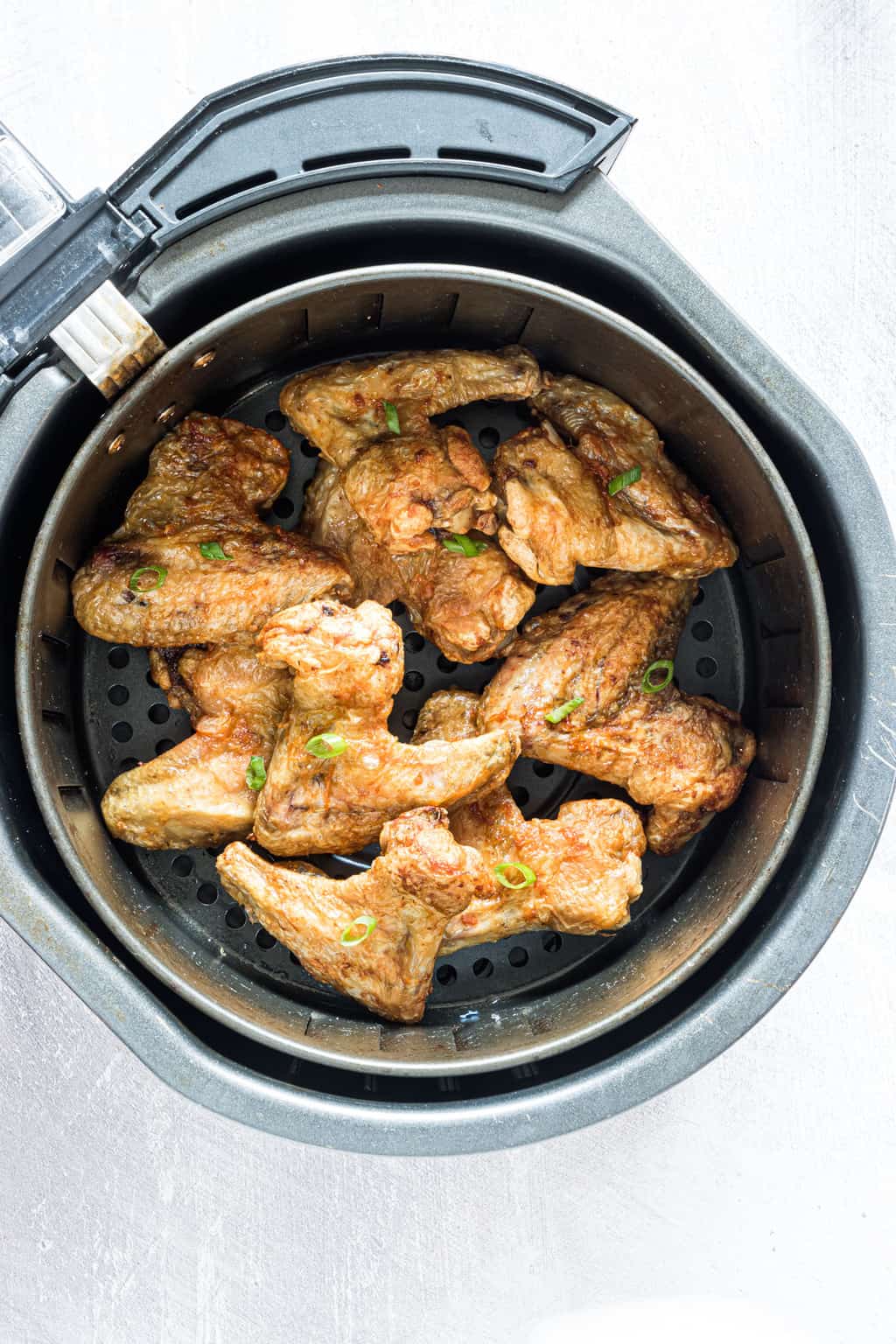 top down view of cooked chicken wings inside the air fryer basket