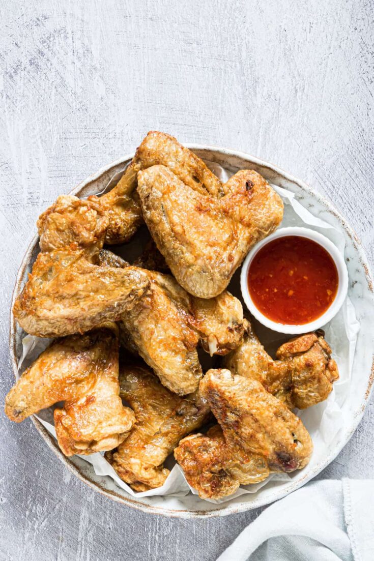 top down view of the completed air fryer frozen chicken wings on a white plate and served with dipping sauce