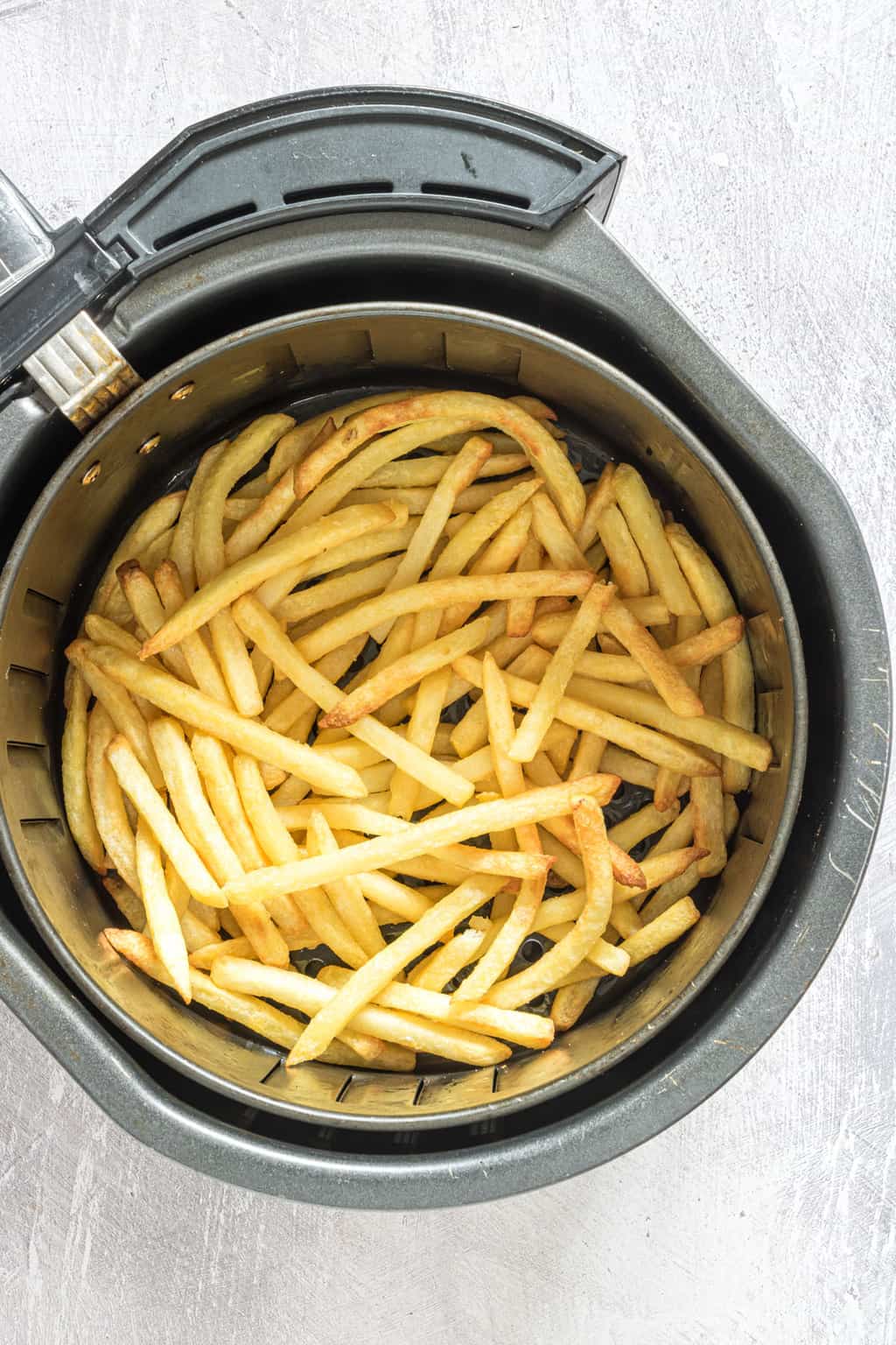 the cooked frozen french fries inside the air fryer basket
