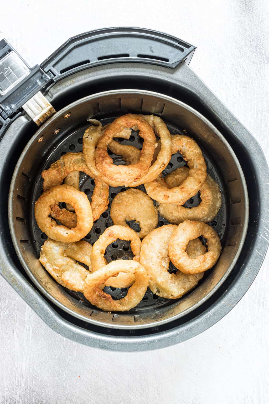 top down view of cooked onion rings inside the air fryer basket