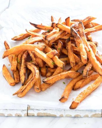 Completed Air Fryer Sweet Potato Fries on white parchment paper and ready to be served
