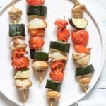 close up of four air fryer vegetable kabobs on a white dinner plate