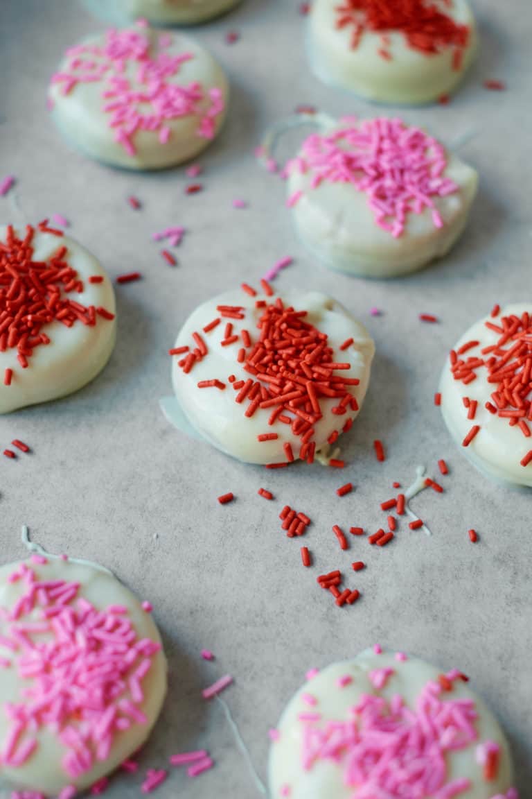 white chocolate covered oreos covered in sprinkles on a baking sheet