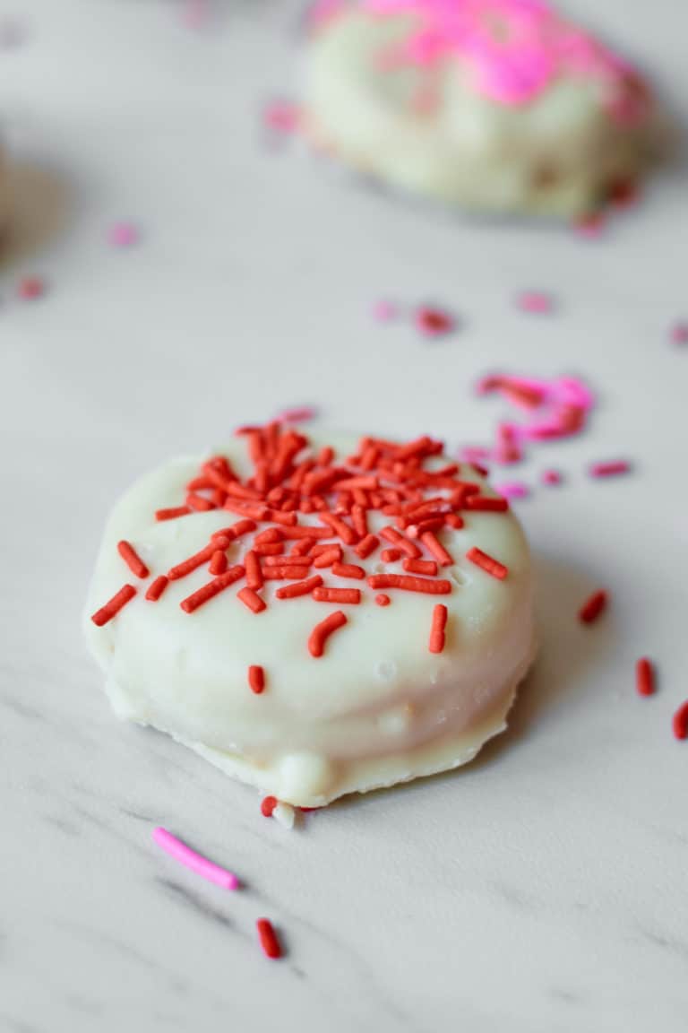 close up of one chocolate covered oreo topped with red sprinkles