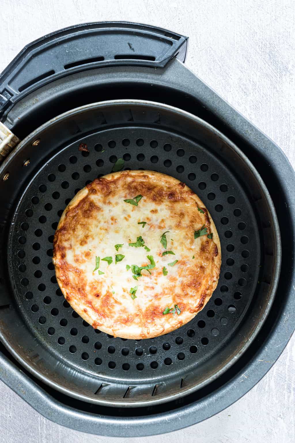 the cooked frozen pizza inside the air fryer basket