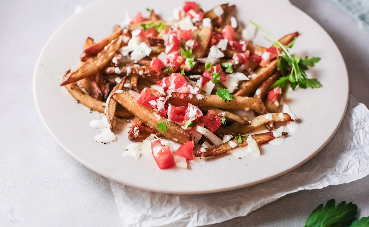 the completed greek fries garnished and served on a white plagte