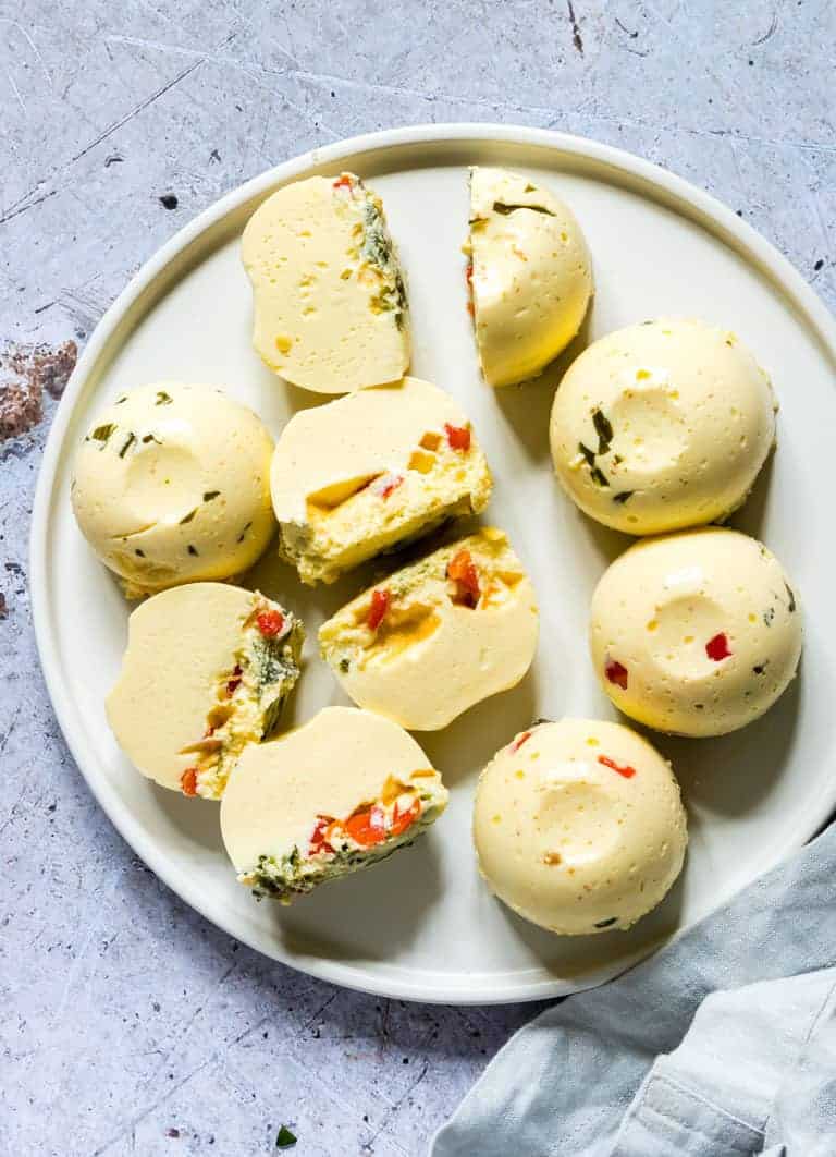 top-down view of a white plate filled with finished Instant Pot Egg Bites set alongside a white napkin and silver fork