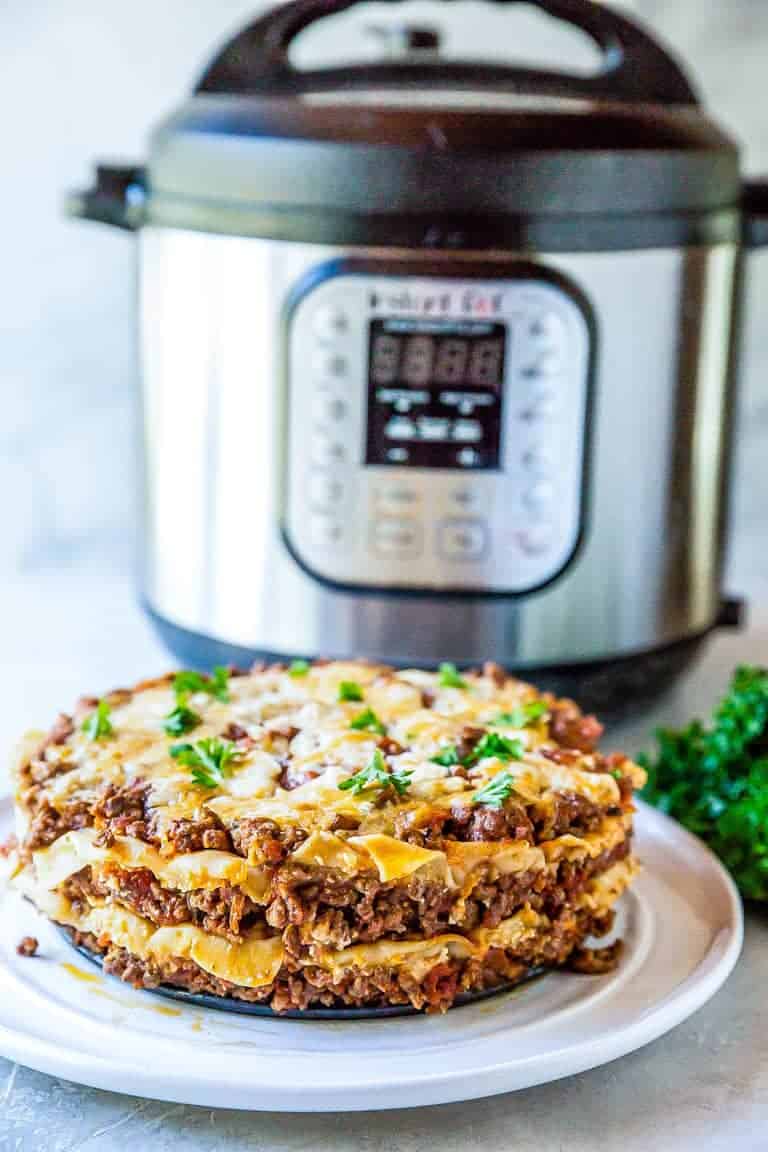 Completed Instant Pot Lasagna served on a white plate and sitting in front of the Instant Pot
