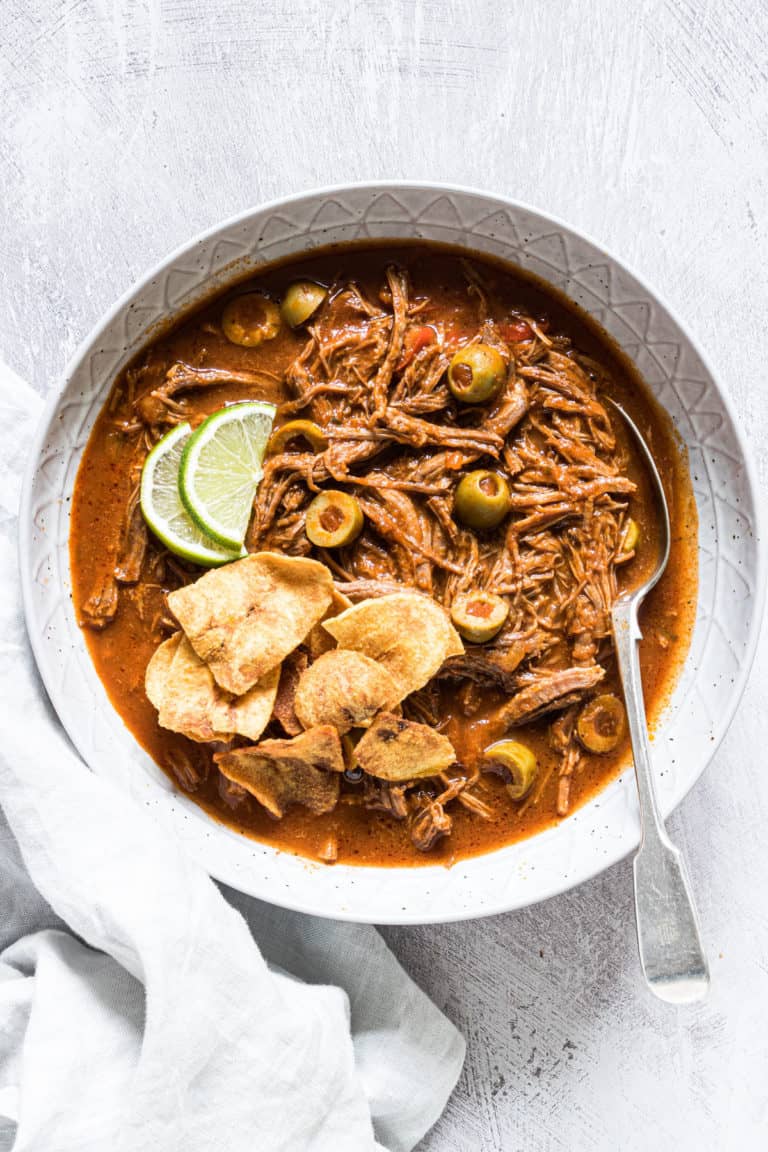 top down view of a serving of instant pot ropa vieja with plantains and lime slices